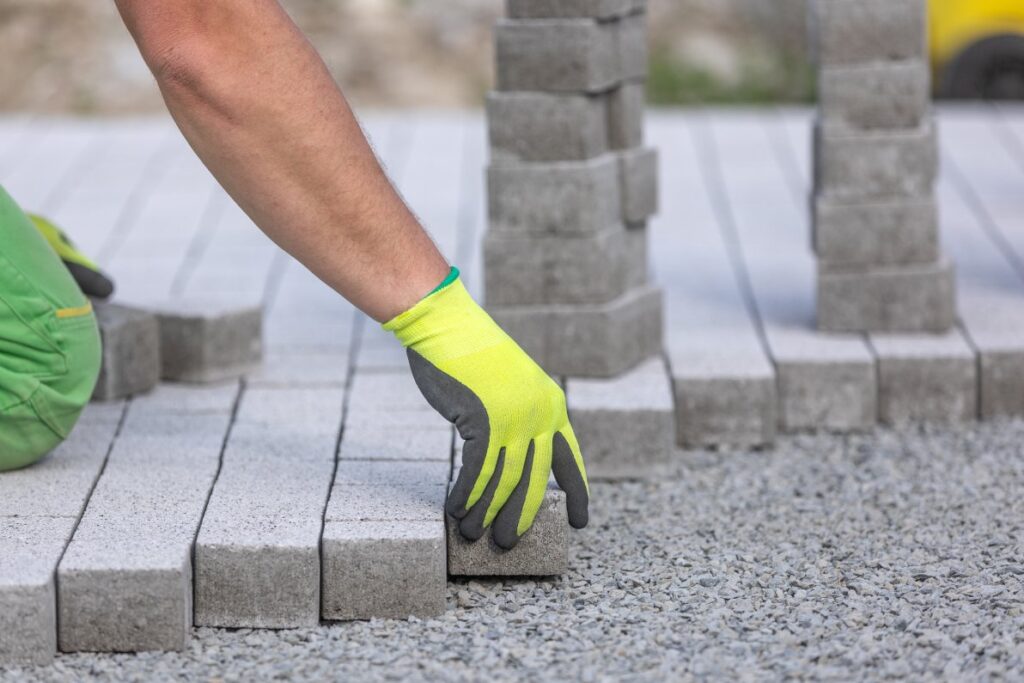Process of building sidewalk worker laying interlocking walking path industrial concept - A Robinson Landscaping Services