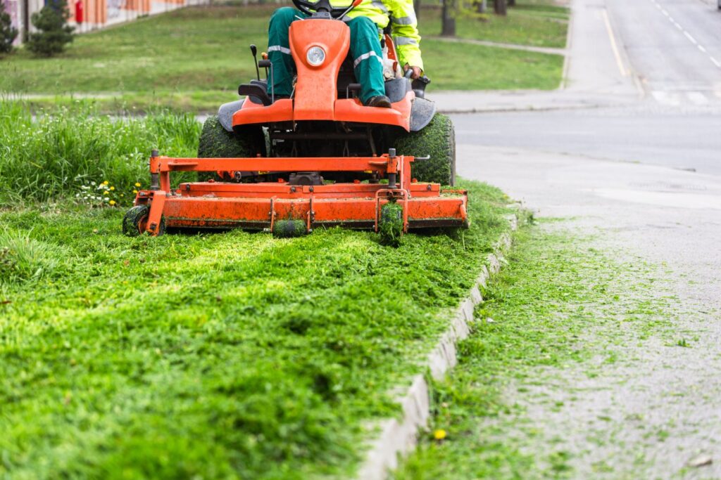 Worker mowing grass with ride-on lawn mower - A Robinson Landscaping Services